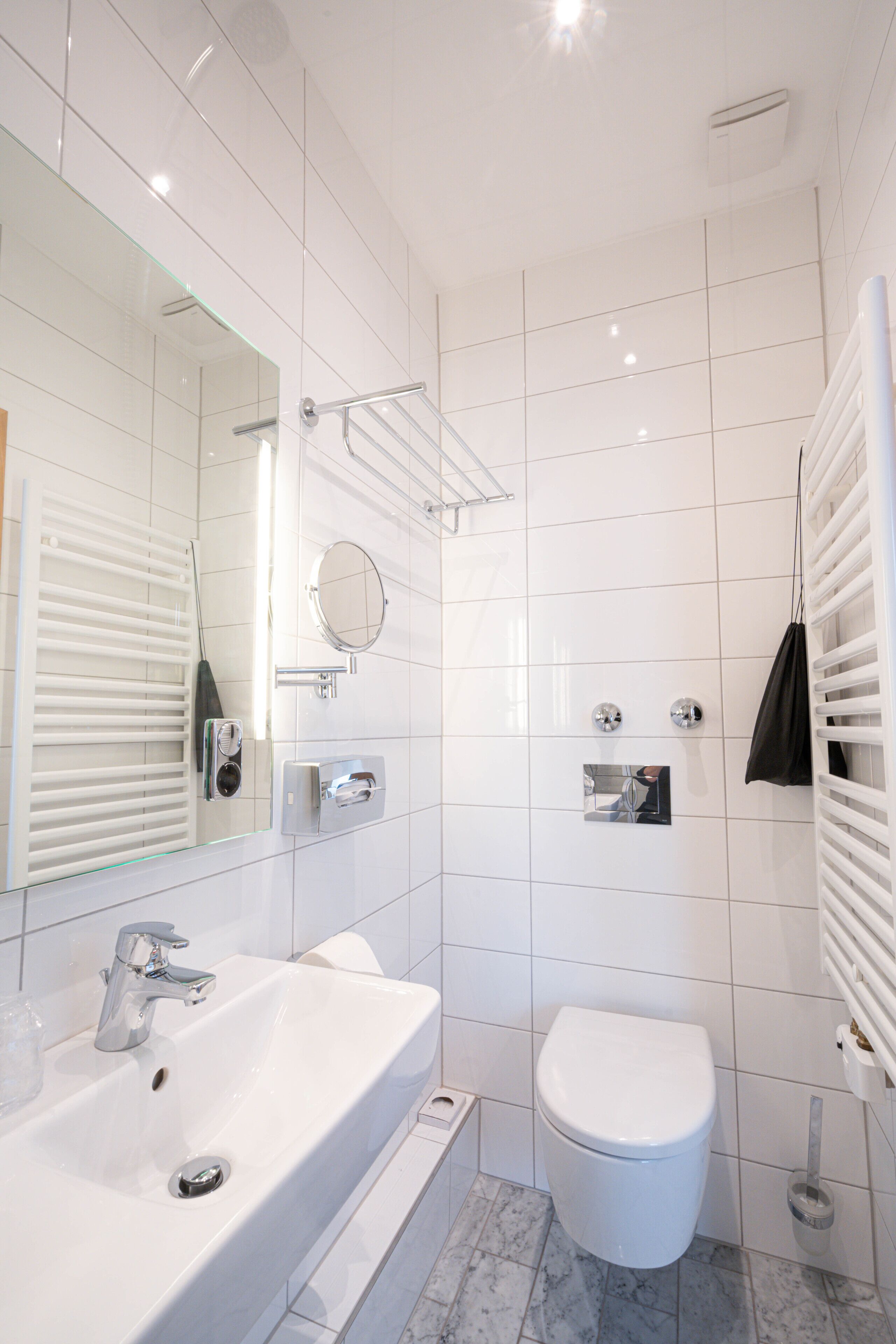 A modern bathroom with a white sink, a toilet, and a mirror.