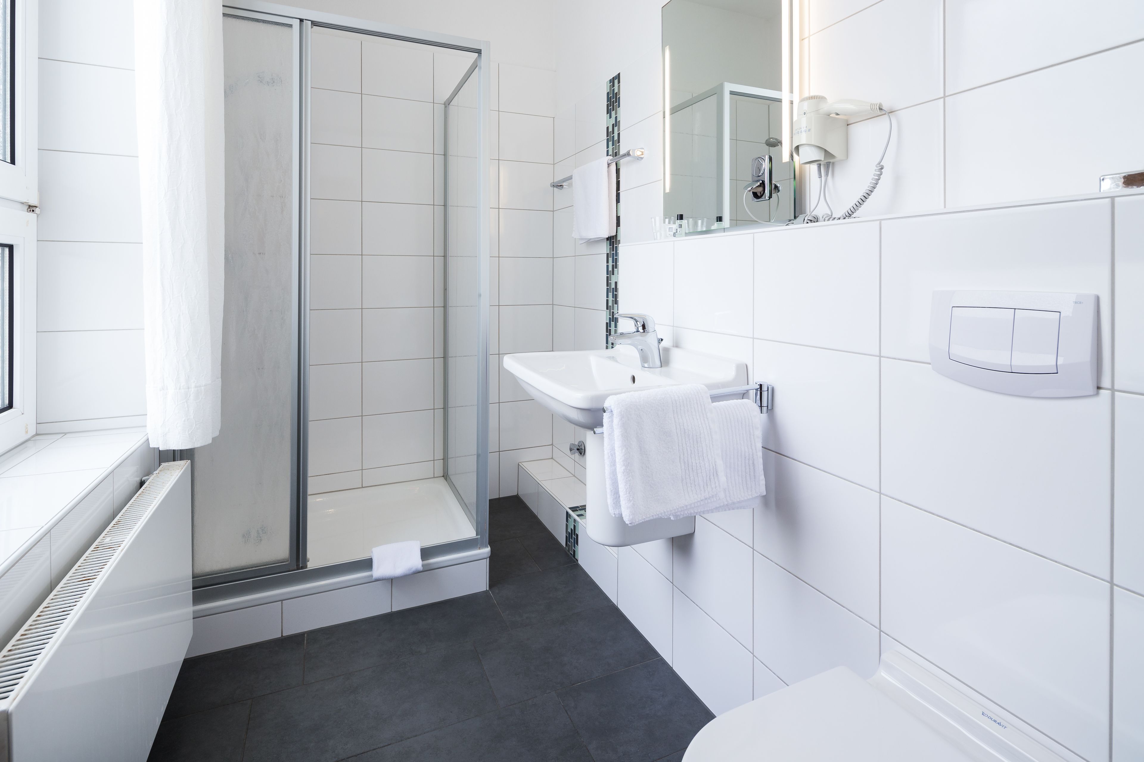 A modern bathroom with a glass shower, white sink, and toilet.