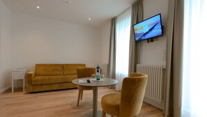 Una sala de estar moderna con un sofá, una mesa redonda y un televisor montado en la pared.