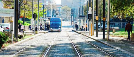 Un tram presso una stazione con diverse linee ferroviarie, cavi aerei e un binario di accesso.