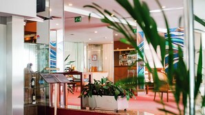A hotel lobby with a glass display case, a reception desk, a staircase, and a bar area. - Premium Porto Maia (Maia)