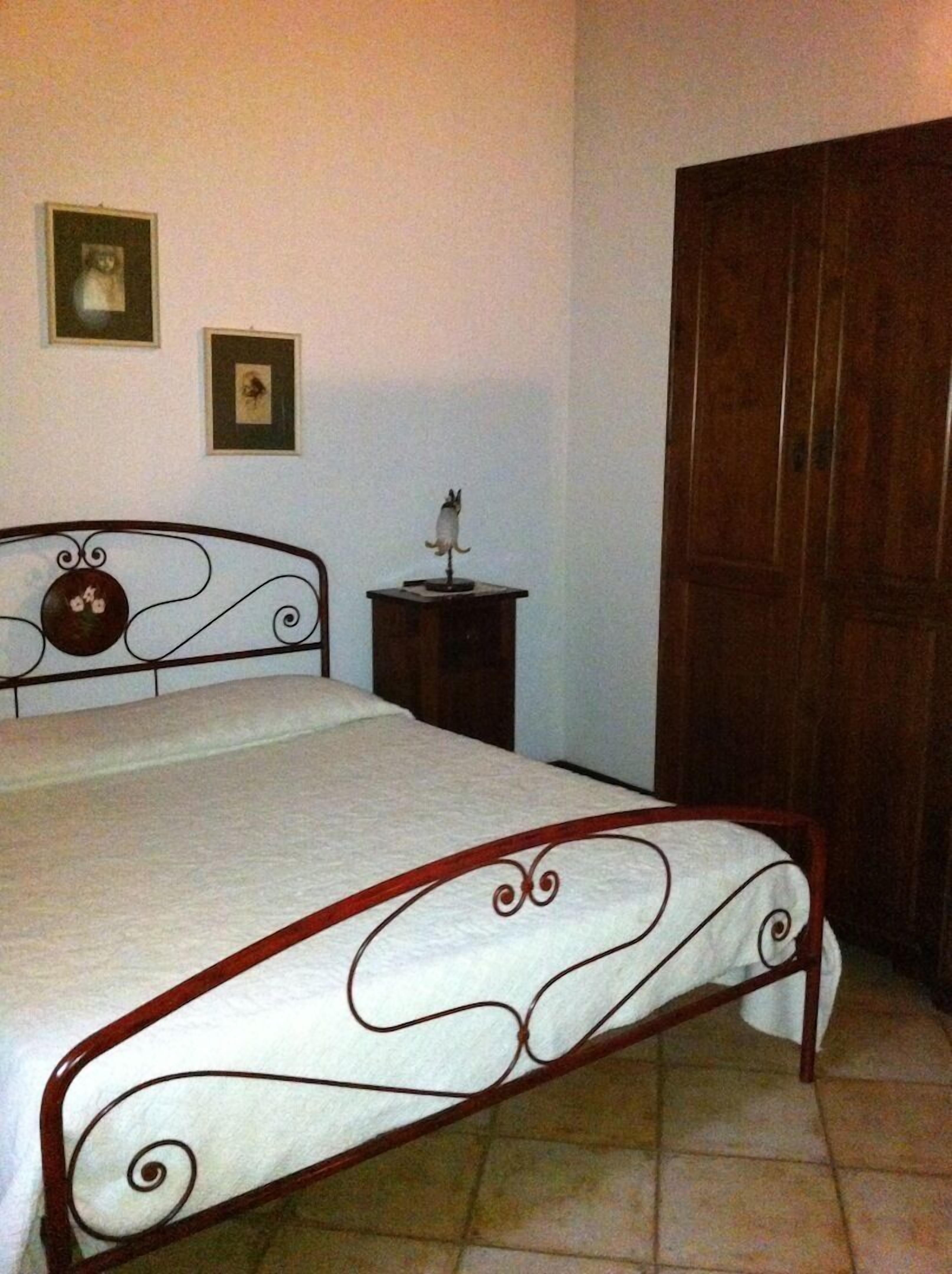 Un dormitorio con una cama, un armario de madera y una mesita con un adorno.