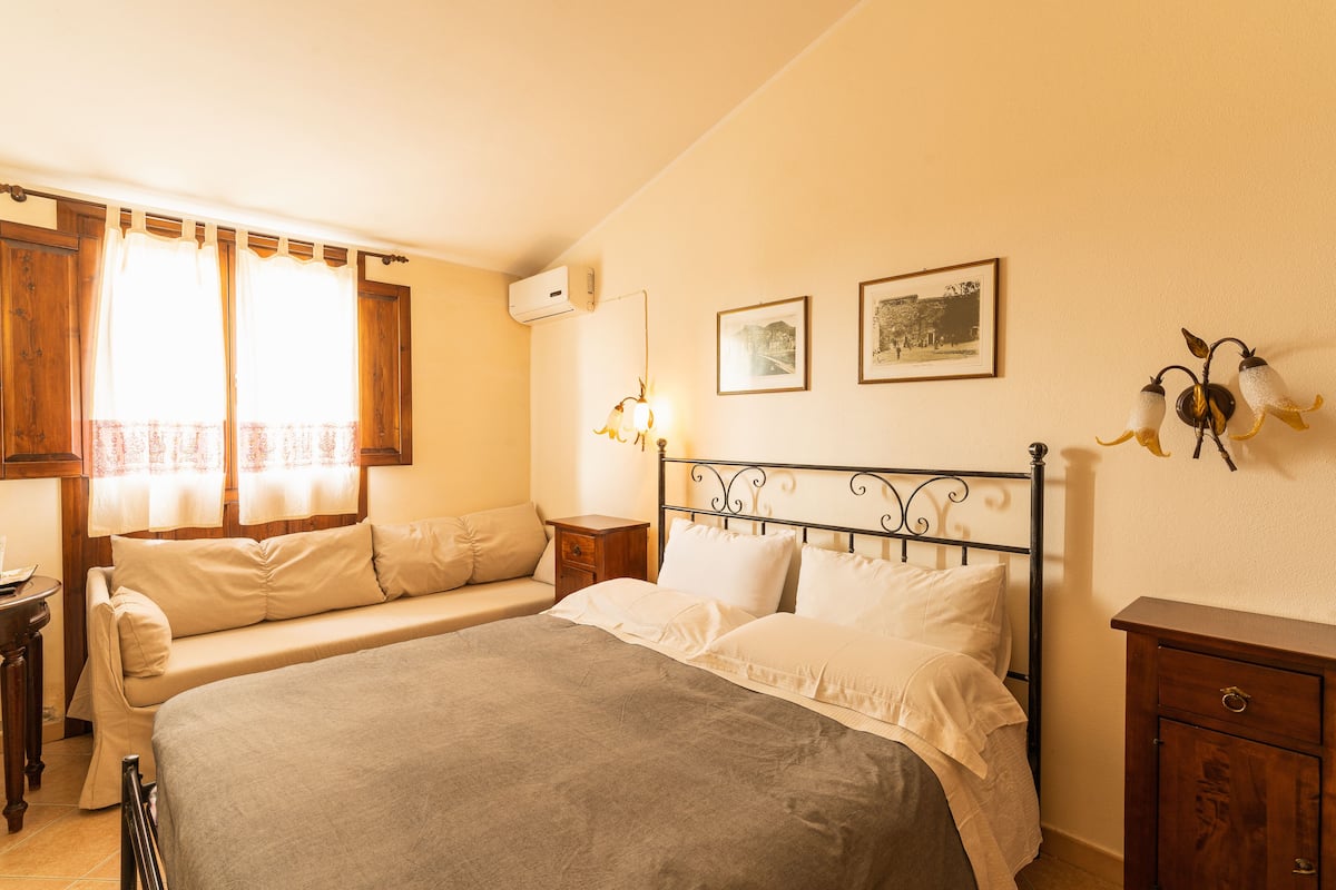 A bedroom with a bed, a nightstand, a dresser, and a window with curtains.