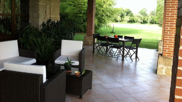 Un patio couvert aménagé avec des meubles en osier, une table et des chaises.