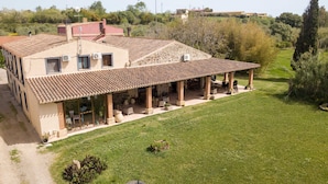 Un bâtiment à deux étages, doté d’un toit en tuiles et d’un patio couvert avec des sièges extérieurs.