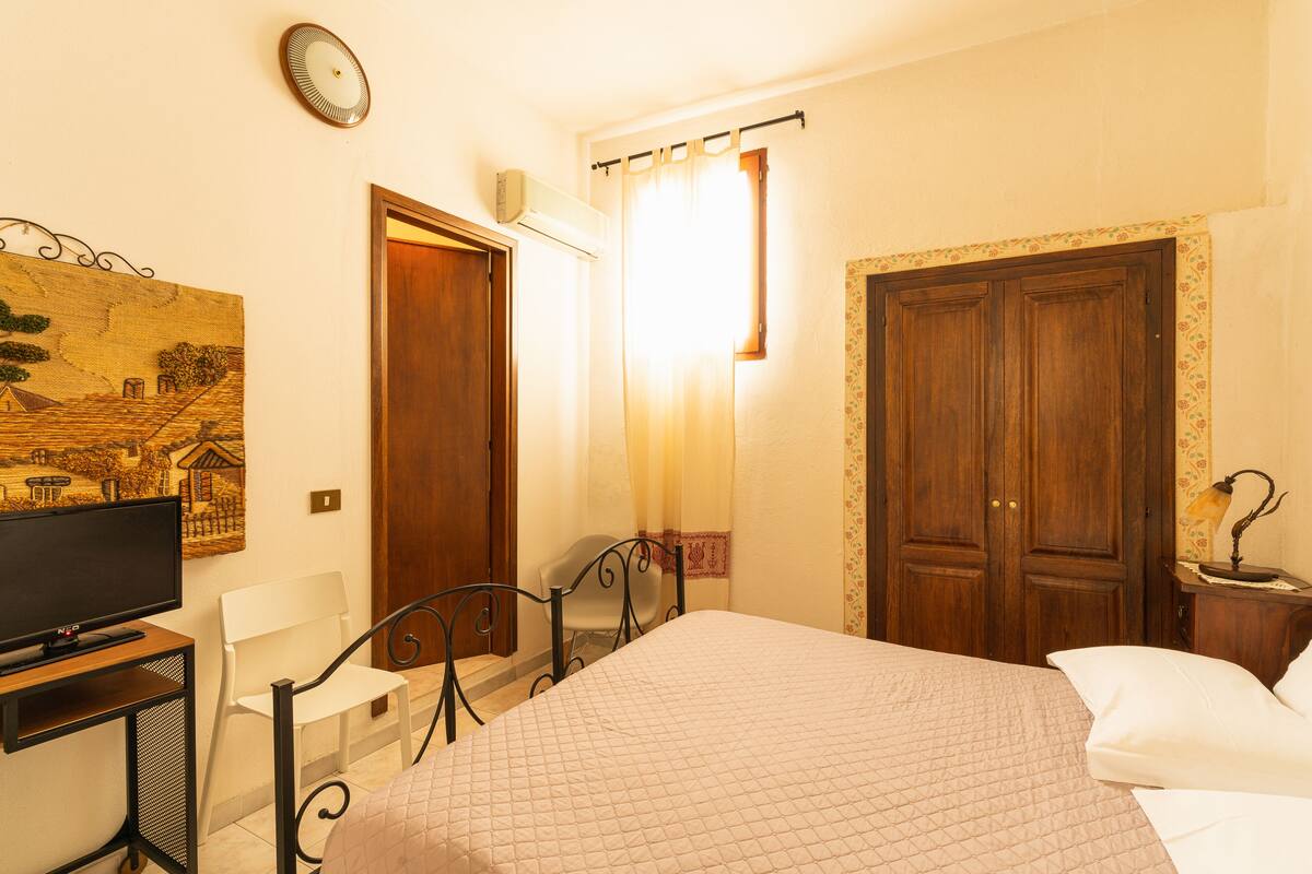A bedroom with a bed, a desk, a chair, a television, and a wardrobe.
