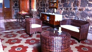 Une pièce aux murs de pierre, un coin repas avec une table et des chaises, et une bibliothèque.