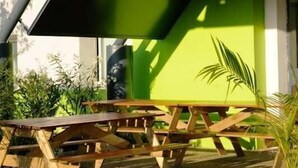 An outdoor seating area with a green wall and a wooden table. - My KB Hotel Montélimar (Saulce-sur-Rhone)