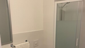 A bathroom with a toilet, sink, and glass shower enclosure. - My KB Hotel Montélimar (Saulce-sur-Rhone)