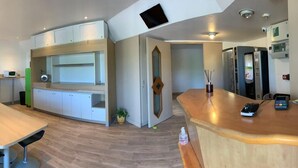 A modern kitchen with a wooden countertop, white cabinets, and a built-in microwave. There is a seating area with a long table and chairs, and a small refrigerator. - My KB Hotel Montélimar (Saulce-sur-Rhone)