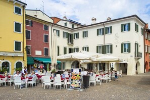 An outdoor cafe with tables and chairs, a menu board, and a building with a sign that reads "Hotel." - Hotel Remàt (Garda)
