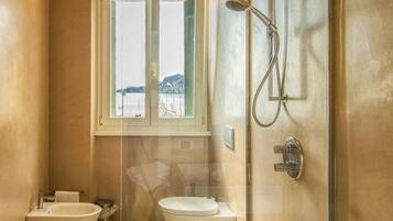 A modern bathroom with a bathtub, two sinks, a shower, and a window overlooking a body of water.