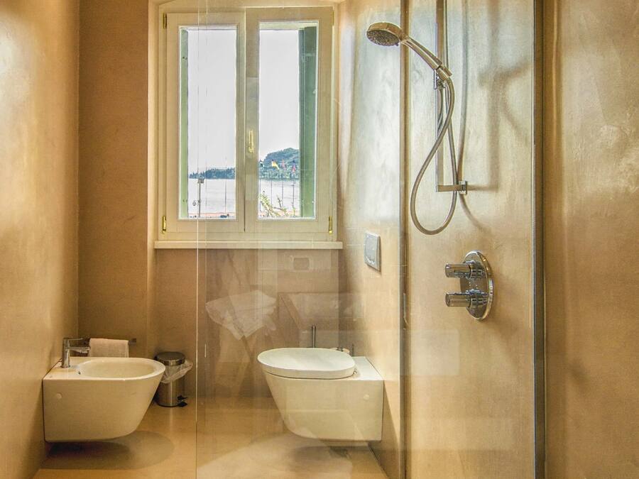Un baño moderno con bañera, dos lavamanos, ducha y ventana con vista al agua.