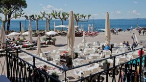 Ein Café am Strand mit Terrassenplätzen, Sonnenschirmen und Meerblick.