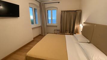 Une chambre d’hôtel avec un lit, un téléviseur fixé au mur et une fenêtre avec des rideaux.