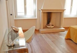 Una habitación con chimenea, un escritorio despejado con lámpara y una cama con colcha amarilla.