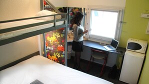 Une chambre de dortoir équipée de lits superposés, d’un bureau avec un ordinateur portable, d’un four à micro-ondes et d’un réfrigérateur.