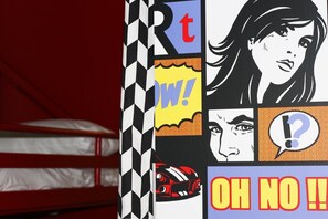 Une pièce avec un lit, un mur orné d’un motif à carreaux noir et blanc, et une affiche aux textes et illustrations graphiques bien marqués.