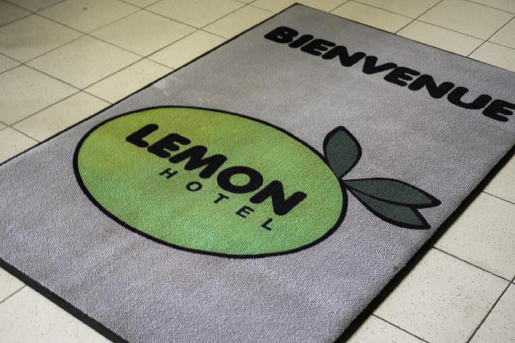 Un paillasson sur lequel sont inscrits les mots « BIENVENUE » et « LEMON HOTEL ».