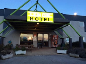 A building with a sign reading "REMOTE HOTEL" and a covered entrance area with benches. - Lemon Hotel Saint Omer (Arques)