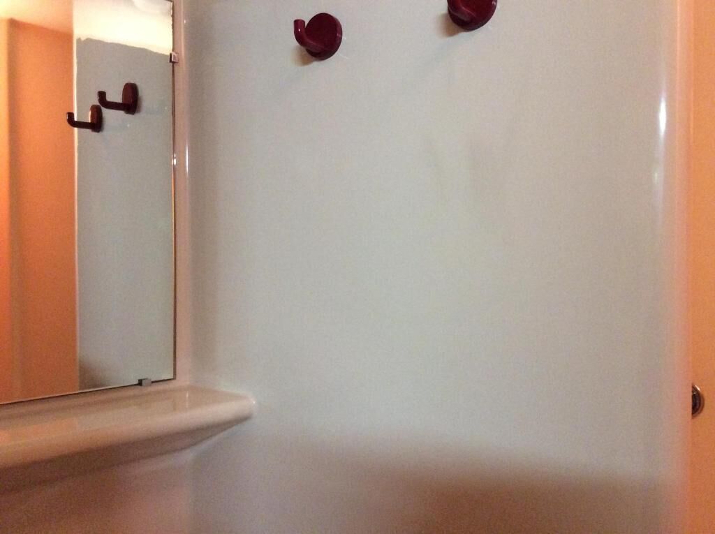 A bathroom with a white bathtub, a mirror, and two red bath spouts.