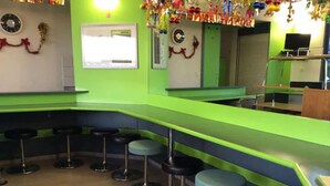 Un espace bar avec des comptoirs verts et des tabourets noirs.