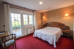 Une chambre à coucher avec un lit double, une table de chevet en bois, une chaise, un bureau et une fenêtre avec des rideaux.