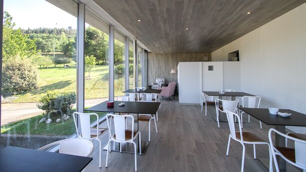 Ein moderner Essbereich mit großen Fenstern, Holzböden und weißen Stühlen.