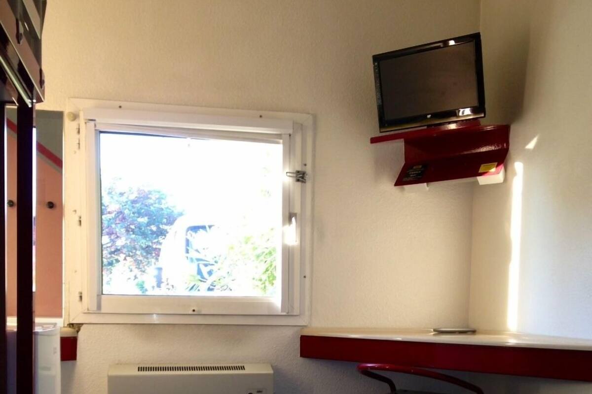 A room with a bed, a window, a heater, a desk, and a TV.