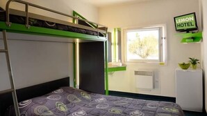 Una habitación con literas, un escritorio, una ventana, un televisor y un refrigerador pequeño.