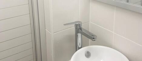 A bathroom with a white sink, a mirror, and a glass shower enclosure.