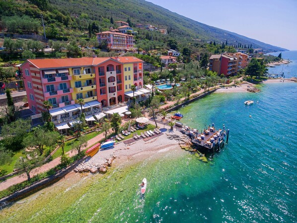 Ein Hotel an der Küste mit mehreren Stockwerken, einem Strandbereich und freiem Blick auf das Meer.