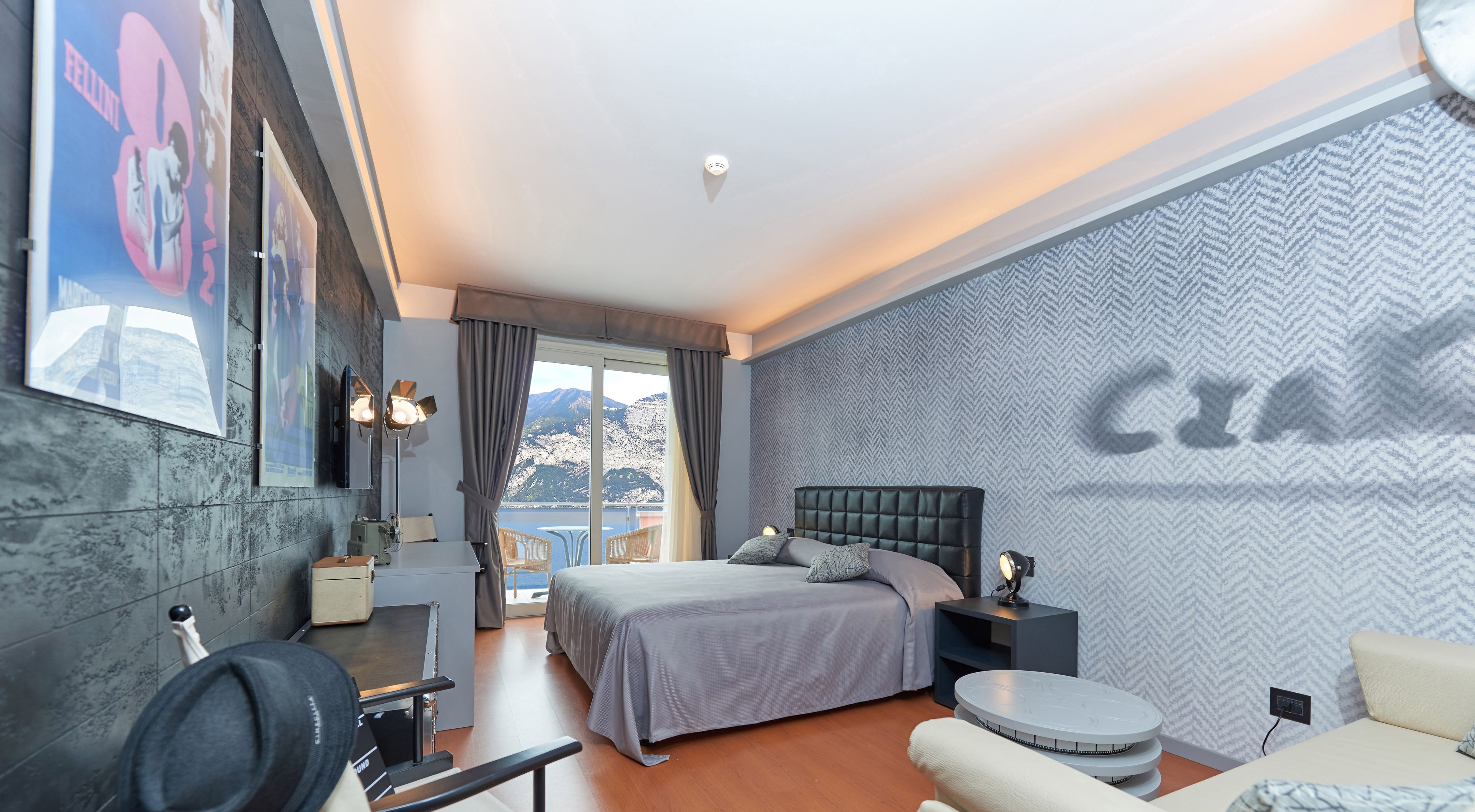 A modern hotel room with a bed, a desk, a chair, and a view of mountains.