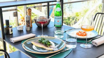 Una mesa con comida, una botella de agua Pellegrino, una copa de vino tinto y un vaso de jugo de naranja.