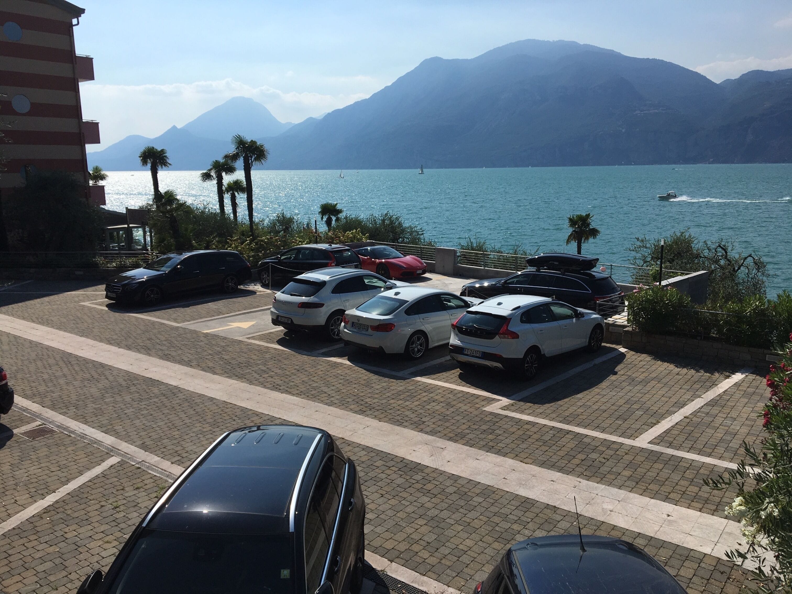 Ein Parkplatz mit Autos, Blick auf einen Berg und einem Gewässer.