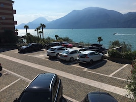 A parking area with cars, a mountain view, and a body of water.