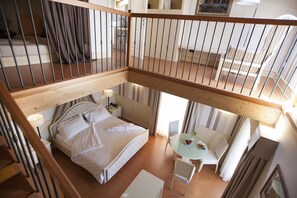 Une chambre d’hôtel avec un lit, une petite table et une chaise, ainsi qu’un balcon doté d’une rambarde.