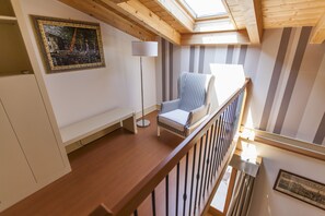 Une pièce avec un plafond en bois, un mur à rayures, une chaise, un lampadaire et un tableau encadré accroché au mur.