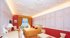 Une chambre d’hôtel avec un grand lit, un bureau, une chaise et une vue sur la mer.