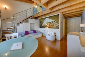 Ein modernes Interieur mit einer Treppe, einem Glastisch, einem Sitzsack und einem großen Gemälde.