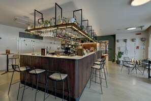 A modern bar area with a wooden counter, multiple seating options, and a variety of bottles and glasses. - Belfiore Park Hotel - Adults Only  (Brenzone sul Garda)