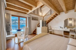 A bedroom with a bed, a desk, a chair, a staircase, and a view of the sea. - Belfiore Park Hotel - Adults Only  (Brenzone sul Garda)