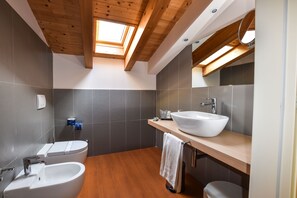 Une salle de bain moderne dotée d’un puits de lumière, d’une baignoire sur pieds, d’un lavabo et de toilettes.