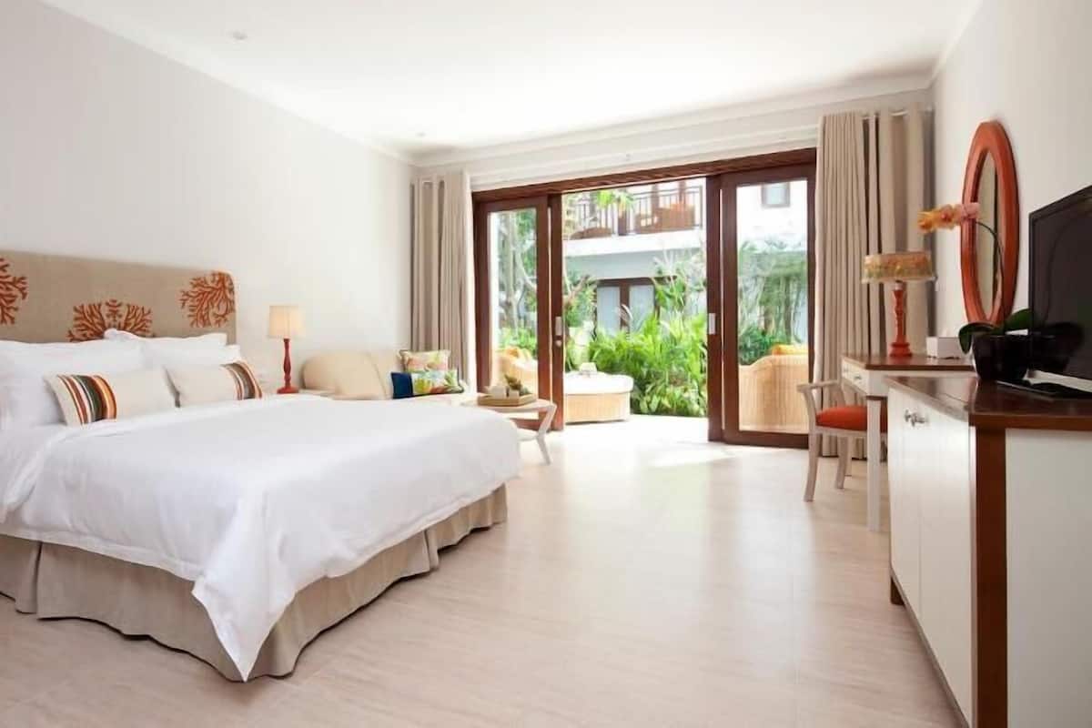 A hotel room with a large bed, a desk, a chair, and a television.
