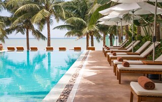 Una piscina al aire libre, sombrillas, sillones reclinables de piscina