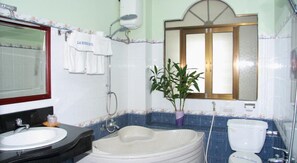 A bathroom with a sink, bathtub, and toilet. There is a mirror above the sink and a window above the toilet. - La Suisse Hotel (Nha Trang)