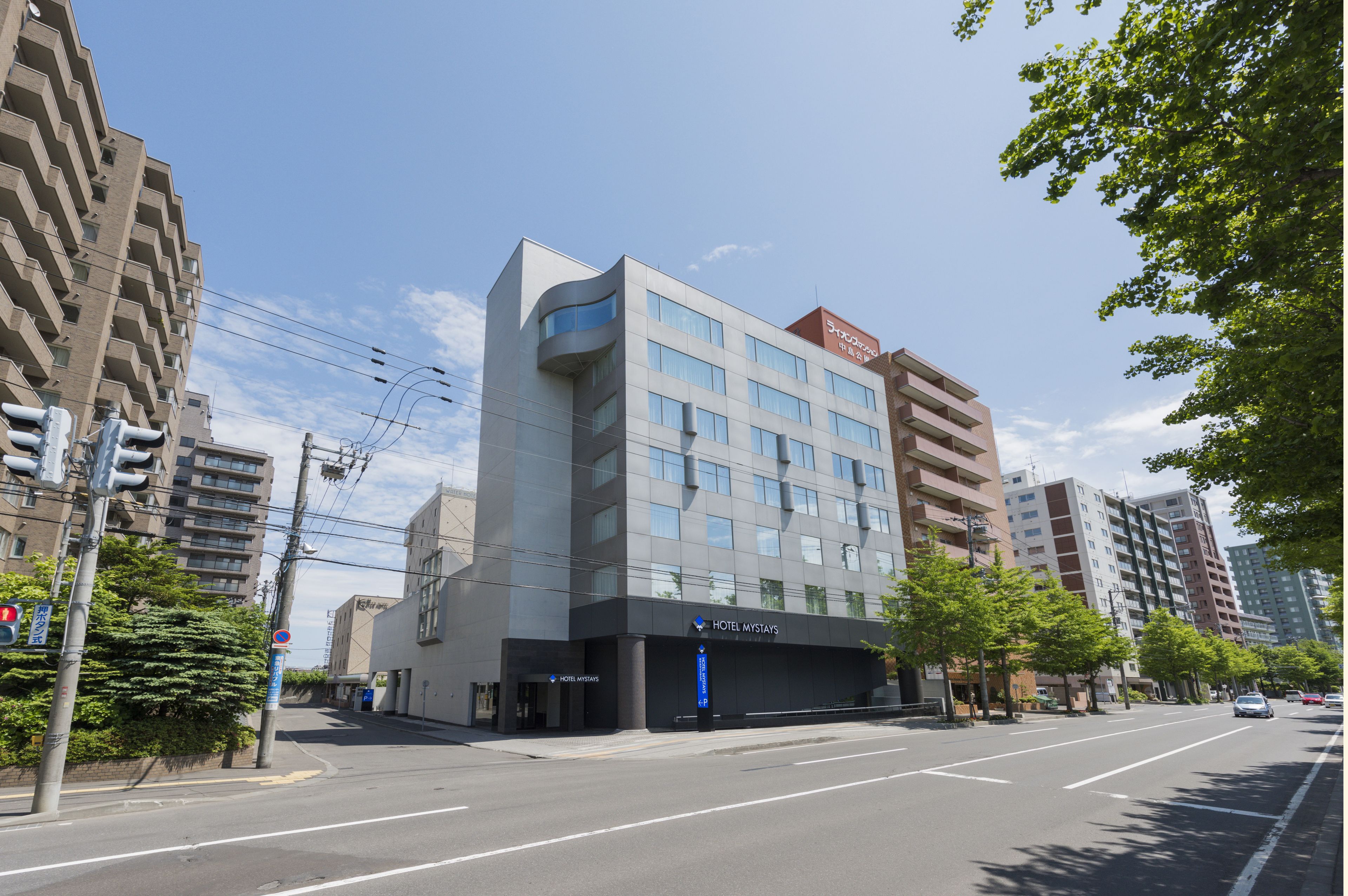 Et moderne hotel med en flad facade, flere etager og store vinduer.