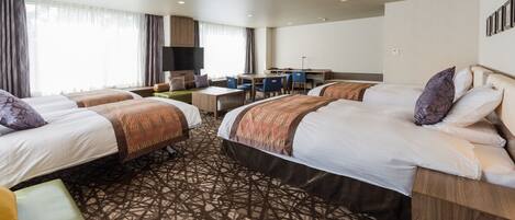 A hotel room with two beds, a desk, a chair, and a TV.