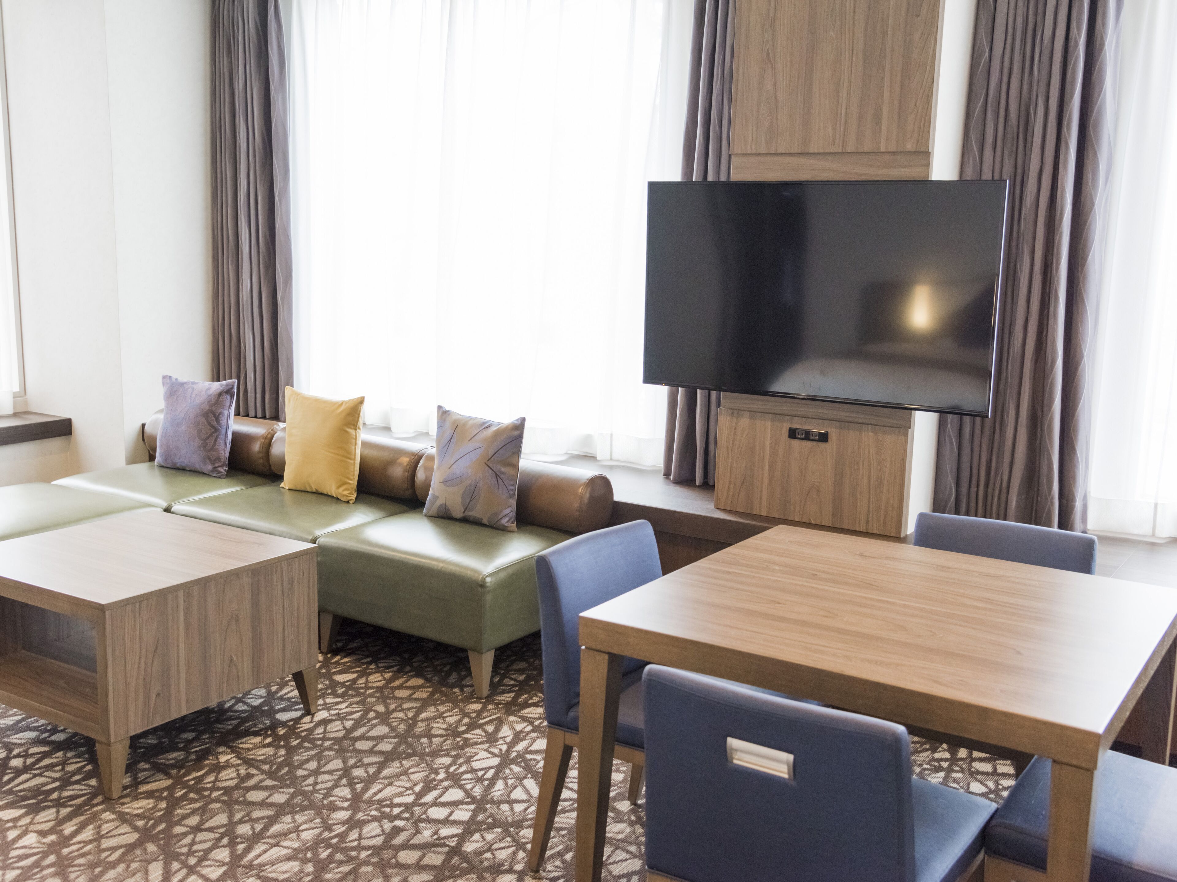 Een hotelkamer met een zithoek, een televisie en een eettafel.
