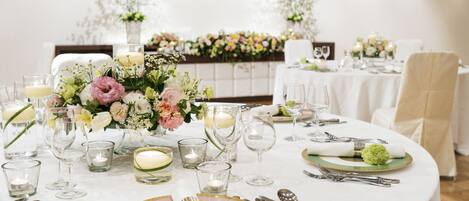 A table set for a formal event with floral centerpieces, candles, and fine china.